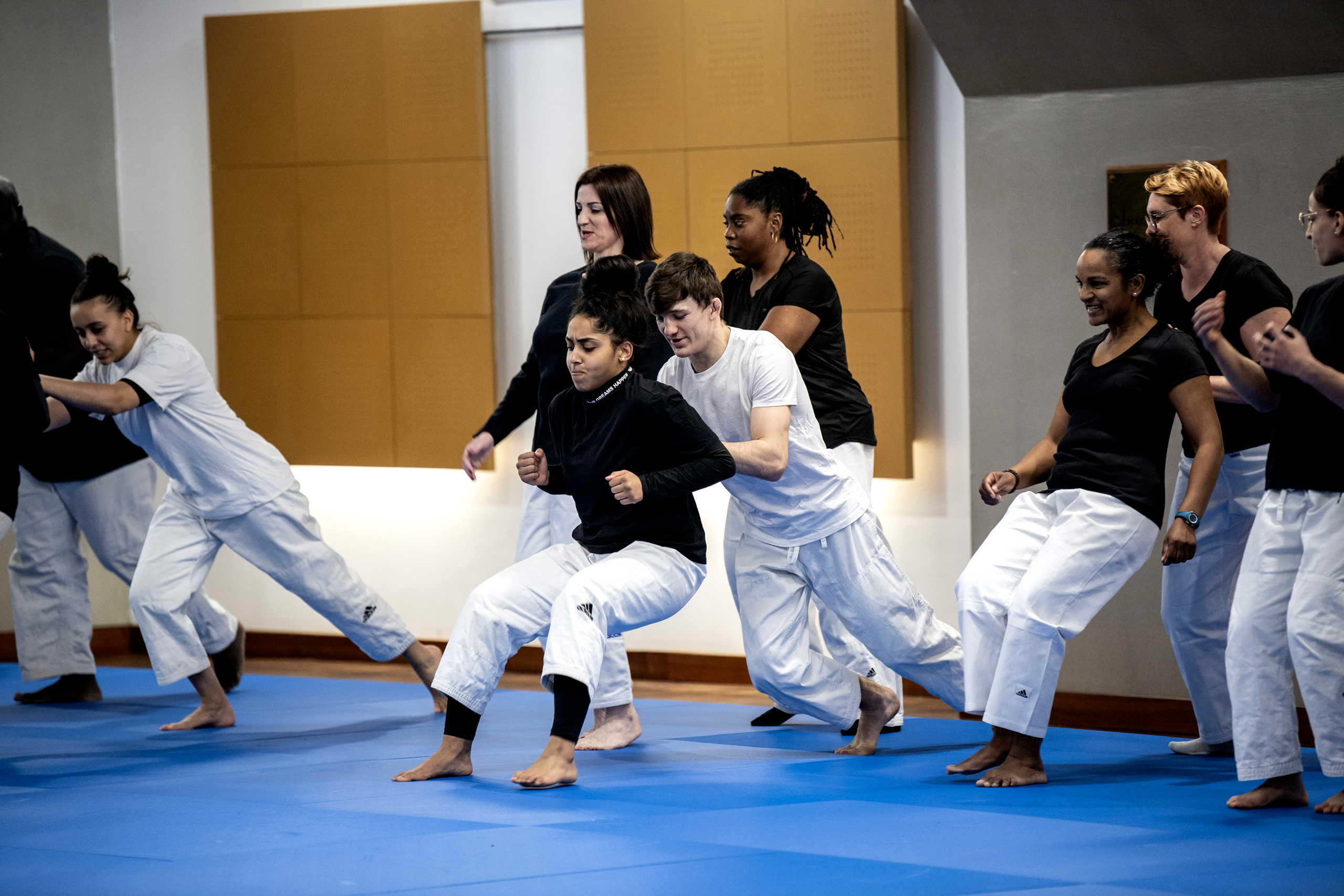 Pratiquants de Taïso en pantalon de judogi blanc et tee-shirt noir en plein exercice en binôme.