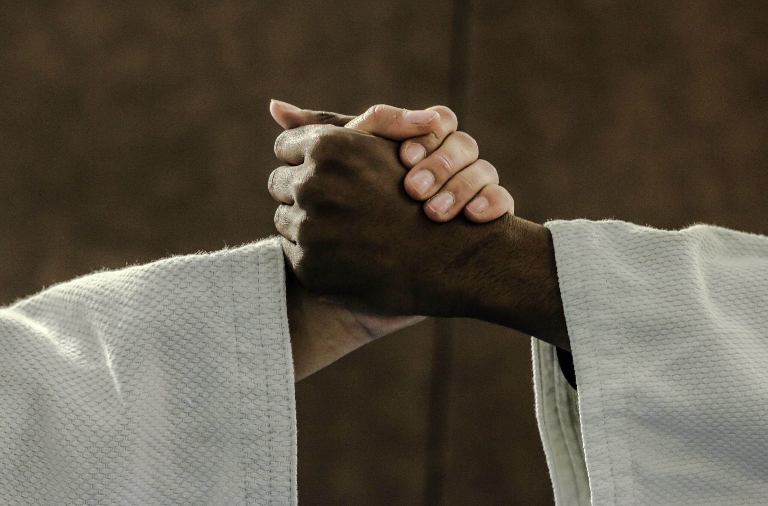 Deux mains de judokas se serrant dans la fraternité.